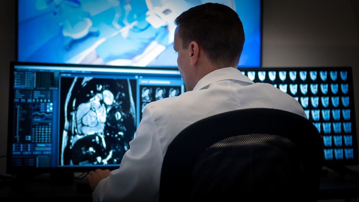 Back view of male radiologist during magnetic resonance imaging scanning. Examination at specialized medical clinic, diagnosis and healthcare concept.